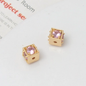 Macro detail of 18k gold plated cube beads with pink zircon inlay for DIY jewelry