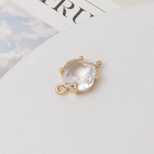 Vue macro d'une breloque en zircon facetté avec deux anneaux de connexion dorés pour bijoux DIY