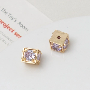 Macro shot of gold-plated cubic charms with purple zircon stones for DIY jewelry making