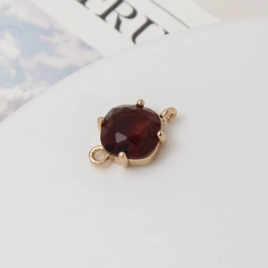 Vue macro d'un connecteur en pierre rouge foncé avec anneaux dorés pour bijoux DIY