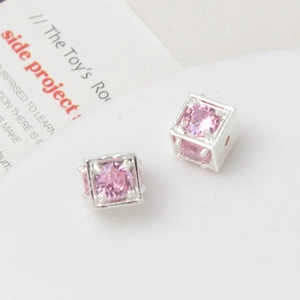 Macro detail of cube-shaped pink zircon beads with silver plated 18k gold frames