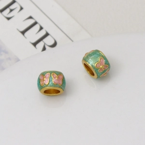 Macro view of mint green enamel butterfly barrel beads with gold plating and glitter