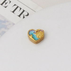 Detailed view of a gold-plated heart bead with a purple enamel finish and rose relief