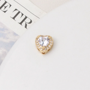 Close-up of gold heart charm bead with zircon inlay for DIY jewelry making