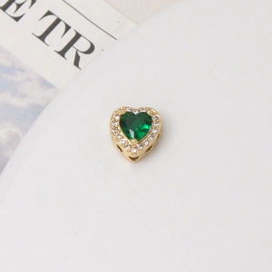 Macro view of heart-shaped green zircon charm with gold plating and halo stones