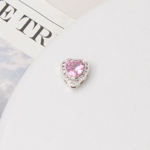 Macro view of heart-shaped charm with pink zircon inlay and pavé set border