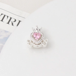Macro detail of pumpkin carriage charm with pink heart zircon and silver crown for DIY jewelry