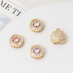 Detailed macro view of four gold-plated spacer beads with zircon heart and lotus designs