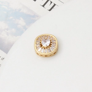 Macro detail of gold plated spacer bead with heart zircon and geometric engravings