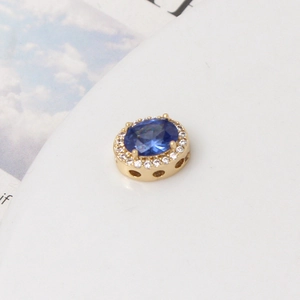 Vista macro de la cuenta ovalada bañada en oro con circón azul y pavé de circonitas