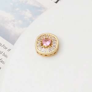 Macro shot of gold square spacer bead with pink heart stone and zircon pave setting