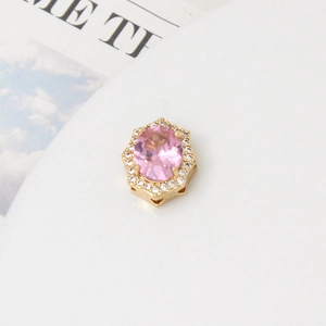 Close-up of golden floral pendant with oval pink gemstone and white zircon accents