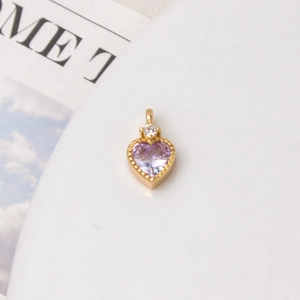 Close-up of heart-shaped purple zircon pendant with gold beaded frame for DIY jewelry