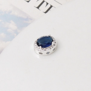 Detalle de dije ovalado plateado con circón azul y cristales pavé para hacer joyería