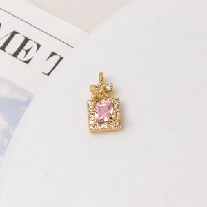 Detailed close-up of a golden perfume bottle pendant with pink gem and butterfly