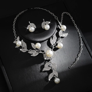 Elegante bloemige bruidssieradenset met parelketting en blad oorbellen op zwart display
