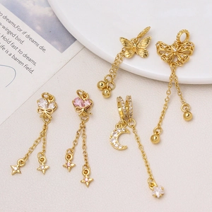 Dettaglio di ciondoli a cuore e farfalla placcati oro 18K con micro-pave di zirconi