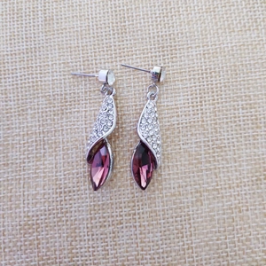 Détail de boucles d'oreilles argentées avec cristal marquise violet et diamants