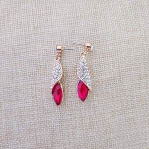 Détail de boucles d'oreilles dorées avec micro-cristaux et pierre marquise rouge