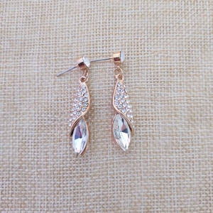 Détail de boucles d'oreilles dorées en forme de feuille avec strass et cristal marquise