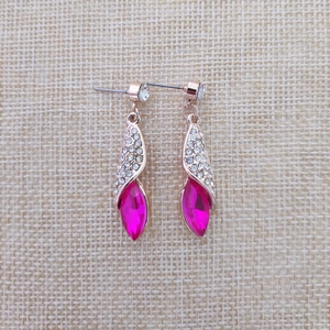 Vue détaillée des boucles d'oreilles en cristal or rose avec strass et pierres rouges