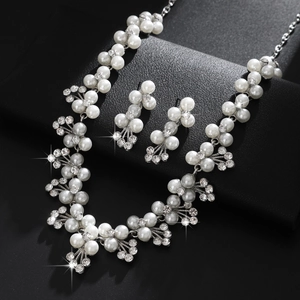 Set gioielli da sposa elegante con perle bianche e strass scintillanti su supporto nero