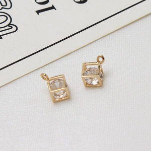 Macro-opname van gouden vierkante zirkonia hangers op witte stof voor DIY sieraden