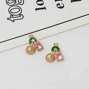 Macro detail of gold cherry pendant with pink and green zircon stones for DIY jewelry