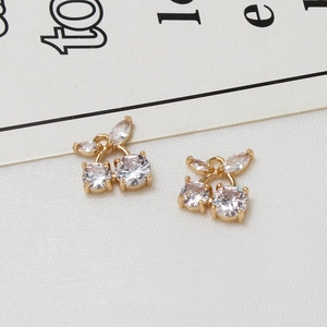 Close-up of gold cherry pendants with inlaid zircon crystals on a white fabric background