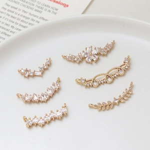 Golden micro-paved zircon leaf and floral jewelry connectors on a white ceramic tray