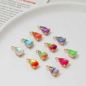 Multicolor gradient 6x10mm teardrop crystal pendants with gold metal settings in a ceramic tray