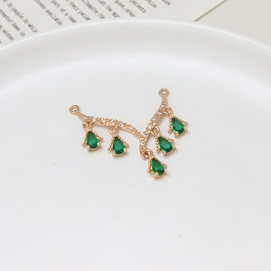 Macro detail of gold V-shaped jewelry pendant with white zircons and green emerald drops
