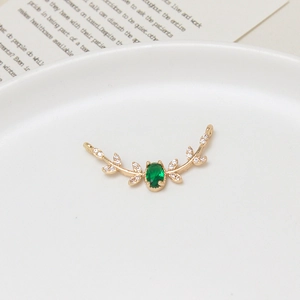 Macro shot of gold willow branch charm with green zircon and side connector loops