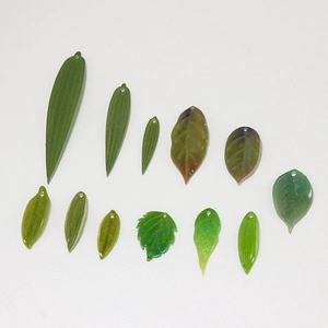 DIY jewelry parts showing green resin leaf pendants with pre-drilled holes for crafts