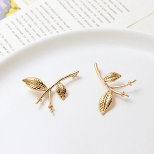 Détail de breloques dorées en forme de branche et feuille pour la création de bijoux