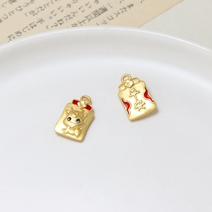 Macro detail of dragon charm and Peace pendant in matte gold with red enamel accents