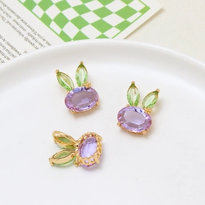 Detailed macro view of three purple crystal rabbit pendants with green gem ears on a plate