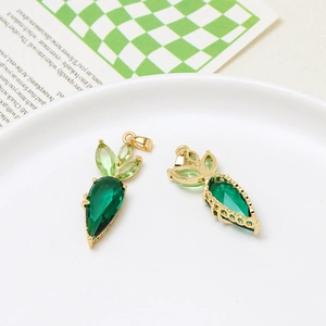 Macro view of carrot-shaped gold pendants with green gemstones and side engraving