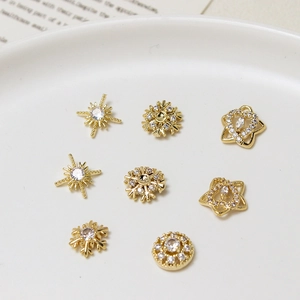 Dettaglio di ciondoli per unghie in oro di lusso con zirconi a forma di stella e neve