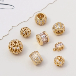 Detail of 18K gold-plated cubic zirconia beads in sphere and hollow heart shapes for jewelry