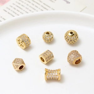 Close-up of gold-plated copper spacer beads with micro-pave cubic zirconia on ceramic tray
