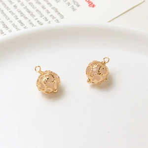 Detailed view of hollow gold-plated metal spherical pendants with pink crystal beads