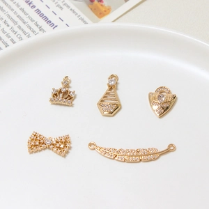 Macro shot of 5 gold-plated zircon charms including crown, bow and leaf for DIY jewelry making