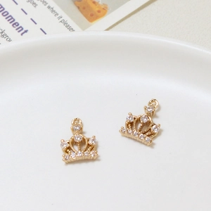 Close-up of golden crown pendants with micro-set zircons on a white ceramic plate