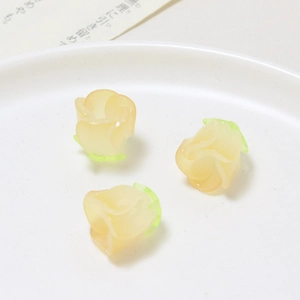 Macro view of cream resin rose petal charms with green base for DIY jewelry crafting