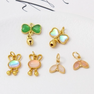 Macro shot of gold-plated butterfly, rabbit, and fishtail charms with opal inlays