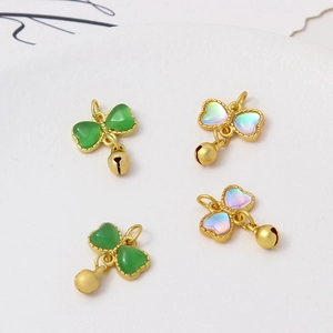 Macro shot of gold bow pendants with green opal finish and small bell charms for DIY jewelry