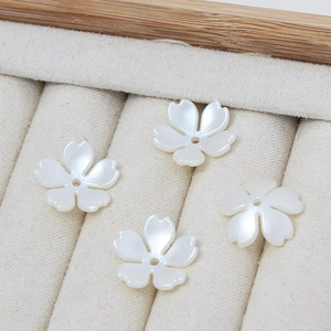 Vista detallada de cuatro cuentas de flores blancas de cinco pétalos para bisutería DIY