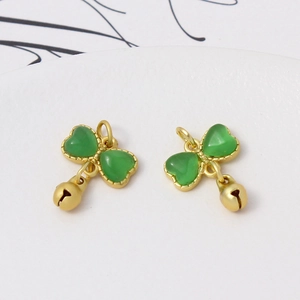 Detail view of gold heart pendants with green stones and hanging bells for DIY jewelry