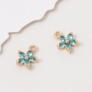 Detailansicht von zwei blauen Blumenanhängern mit Goldfassung für DIY-Schmuckherstellung